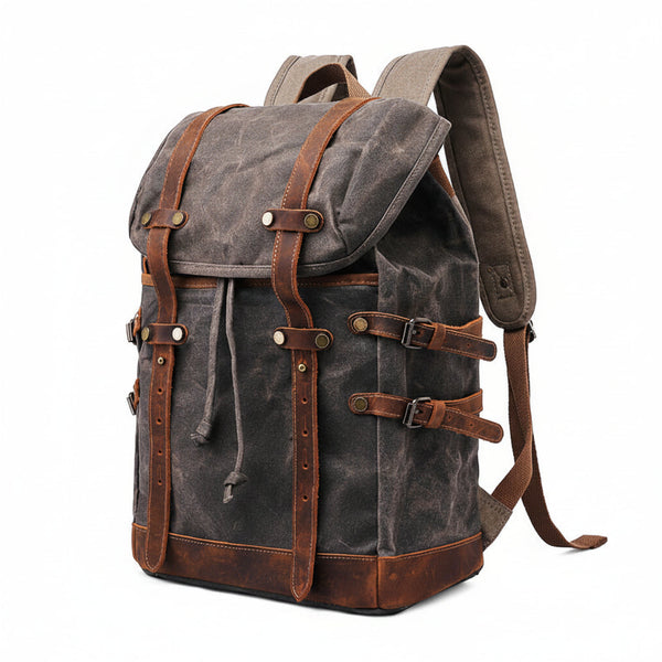 A dark grey waxed canvas rucksack showing the creasing and wear pattern the finish develops