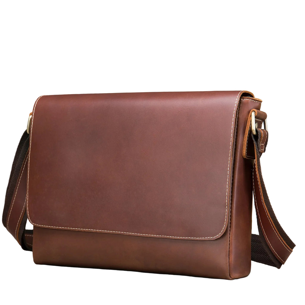 Brown leather flap-front messenger bag with an adjustable shoulder strap and brass-tone hardware, shown at an angle against a white background