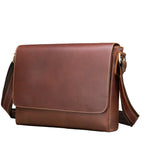 Brown leather flap-front messenger bag with an adjustable shoulder strap and brass-tone hardware, shown at an angle against a white background