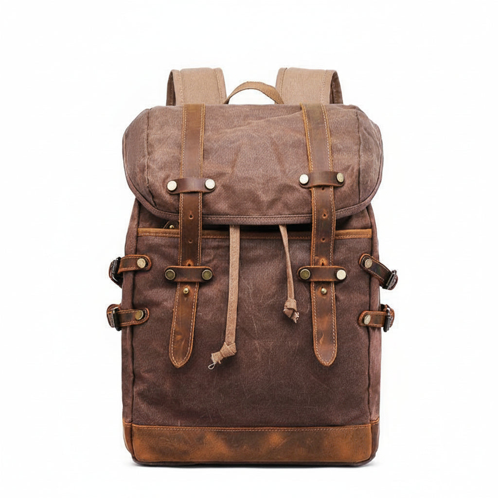 A brown waxed canvas backpack with tan leather straps and metal snap closures, shown against a plain white background 