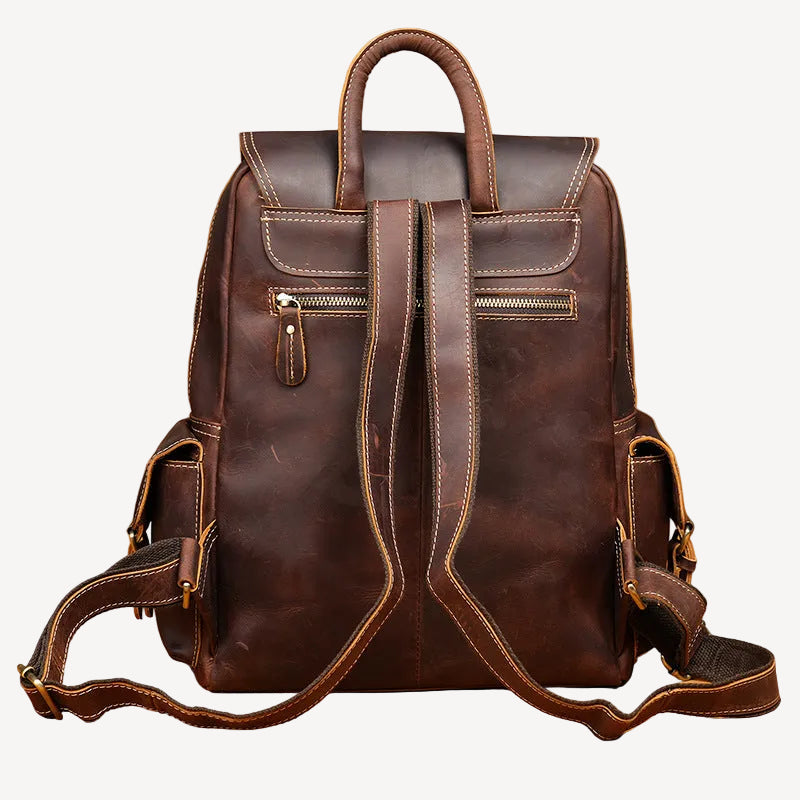 A dark brown distressed leather backpack with top handles, front zippered pockets, and adjustable shoulder straps, displayed against a warm tan textured background.