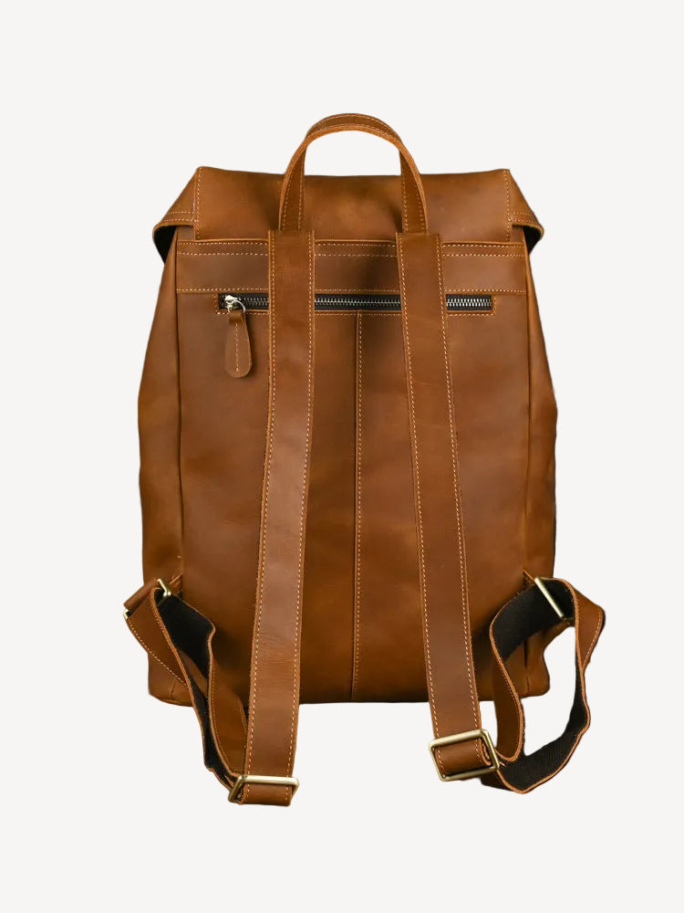 Brown leather backpack on a wooden surface with a dark background