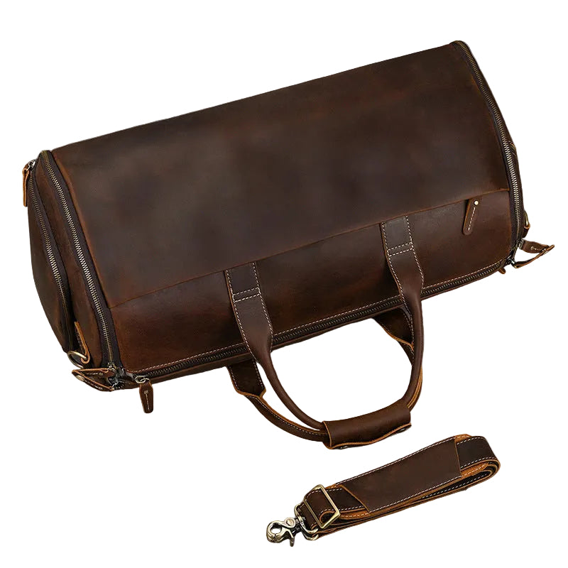 Brown leather duffel bag with strap on a gray background