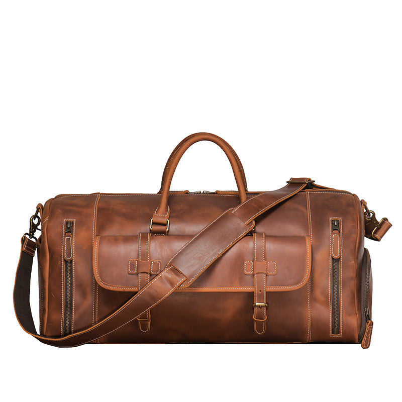 Brown leather barrel duffle with twin rolled handles and a detachable shoulder strap, shown from the front against a white background