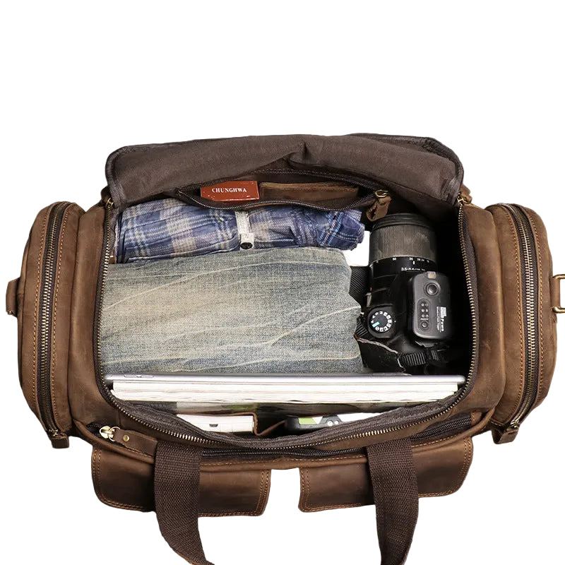 Interior of the Khal Gold Windsor leather holdall packed with folded clothes, a camera and a laptop in the main compartment